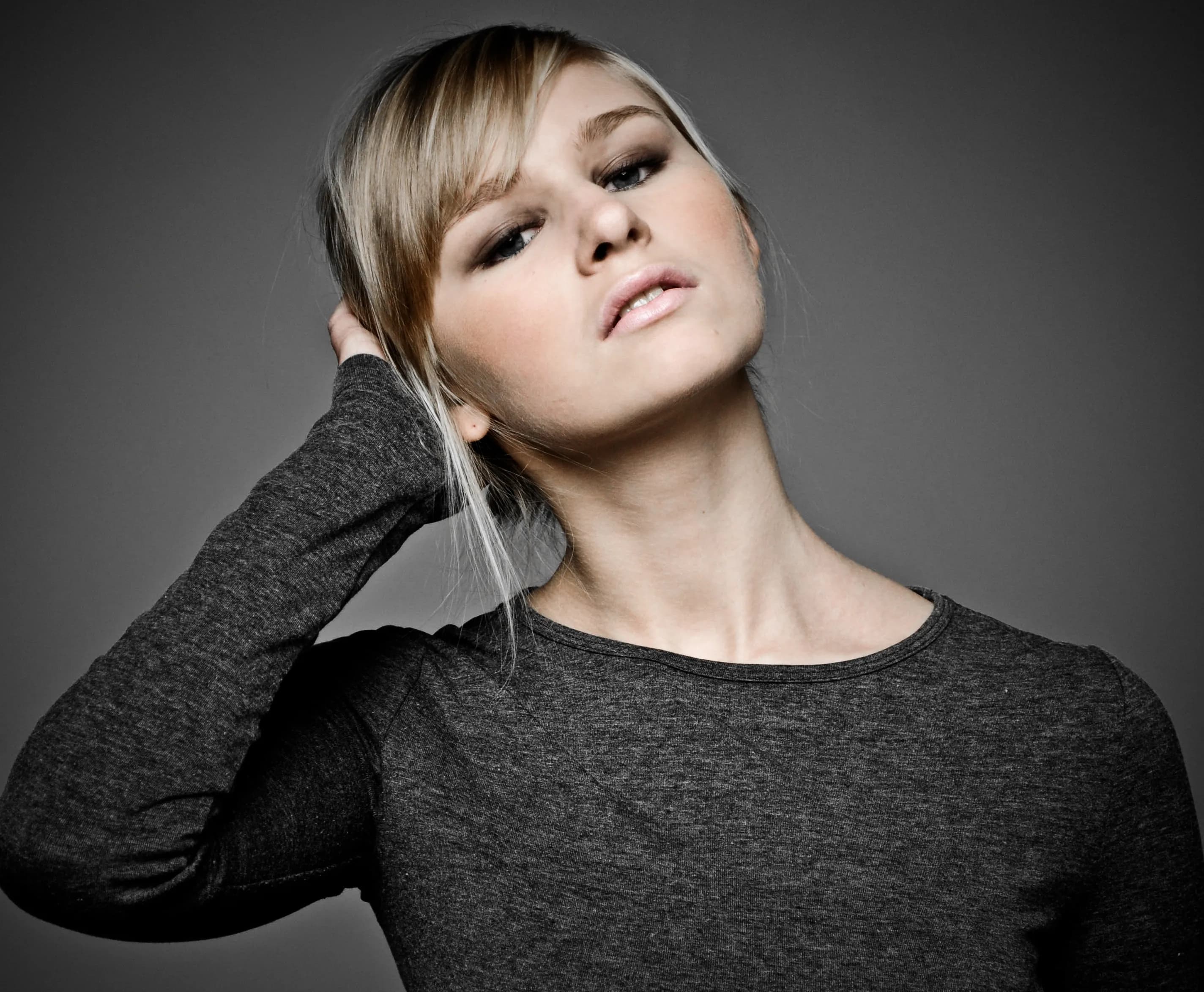 Emily posing with her hand in her hair, wearing a dark long-sleeve top.