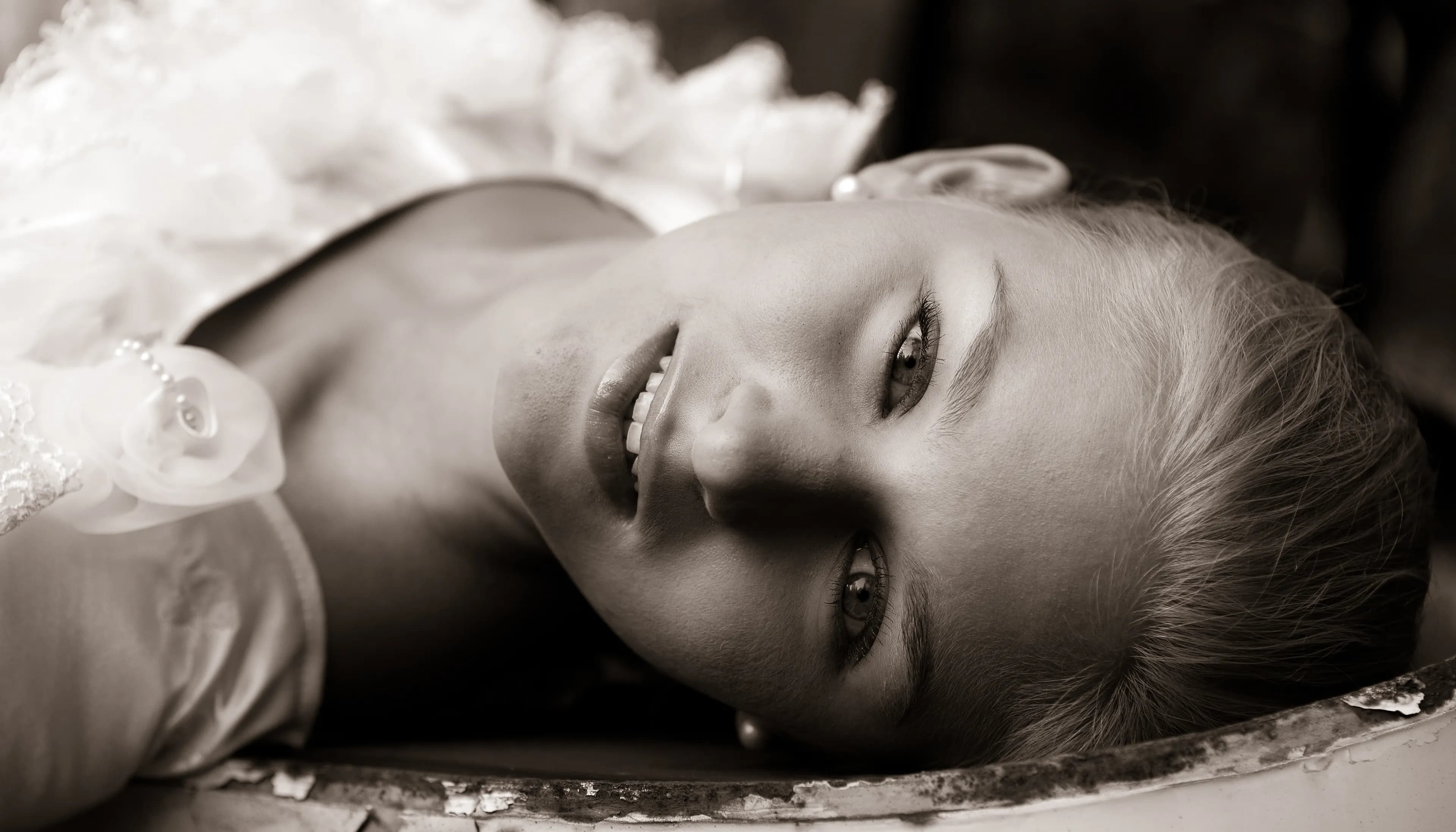 Emily lying down with a serene expression, wearing a white outfit.