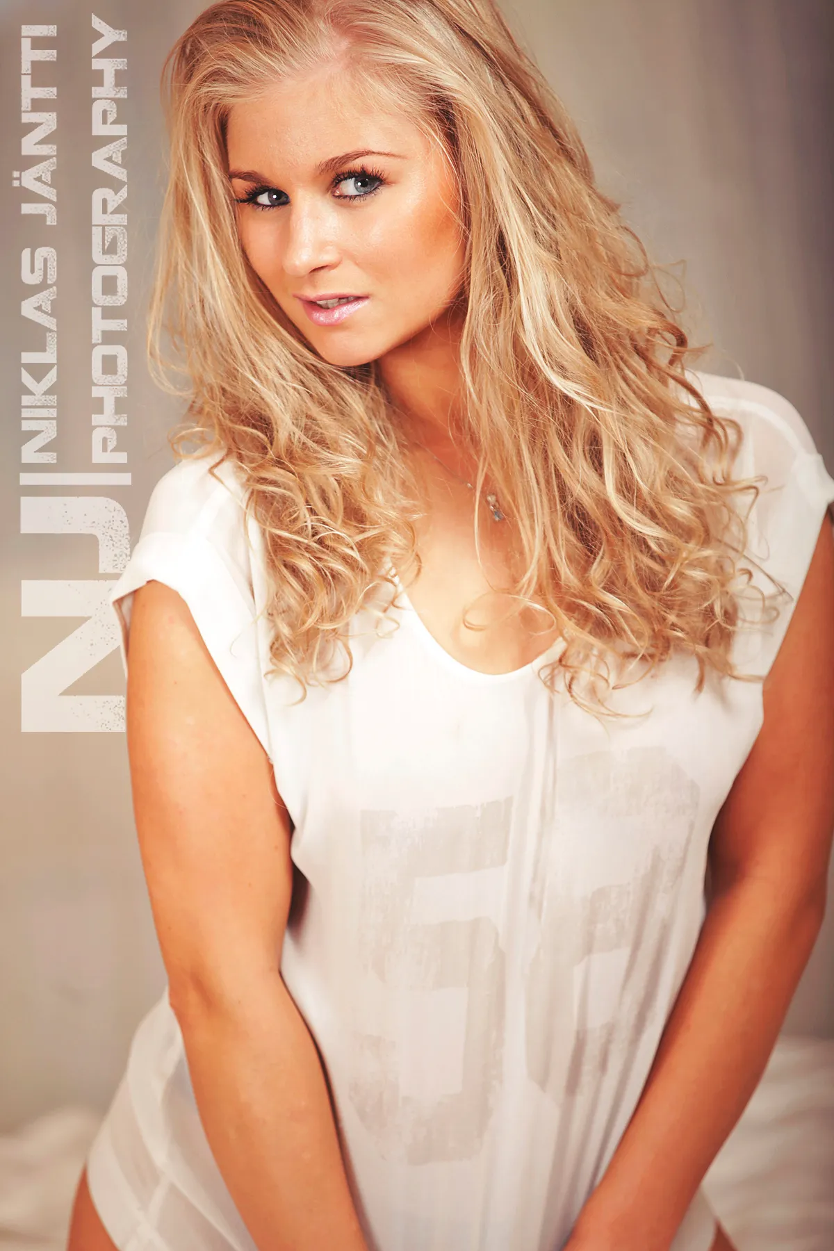 Emily with long curly blonde hair wearing a white top.