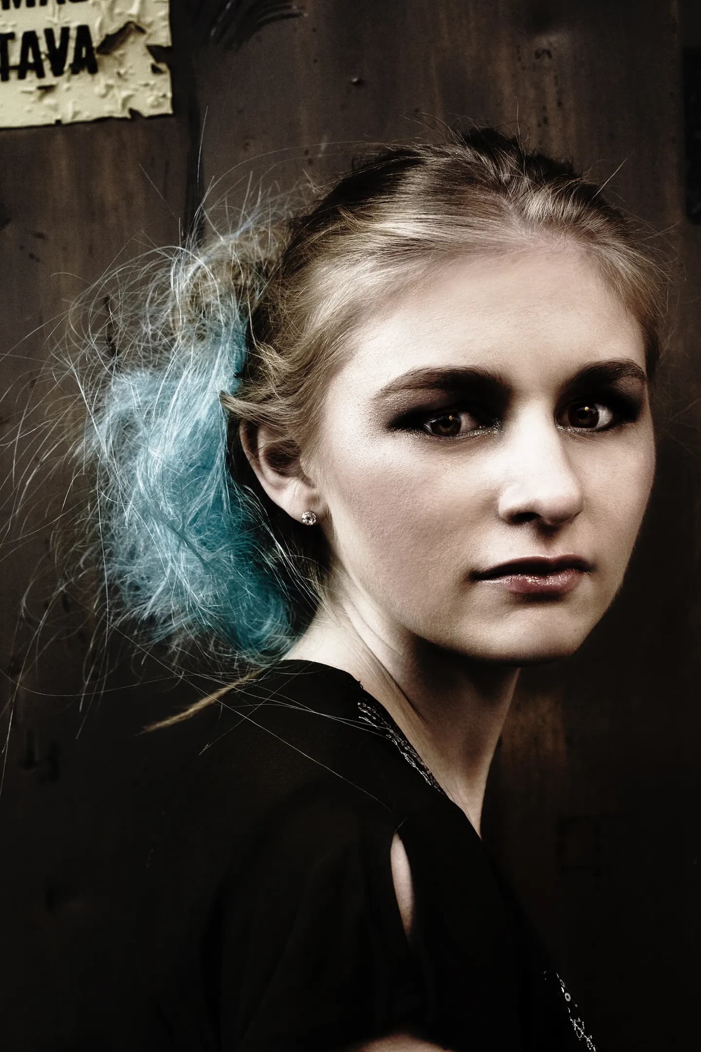 Emily with blue hair highlights, wearing a black top, looking at the camera.