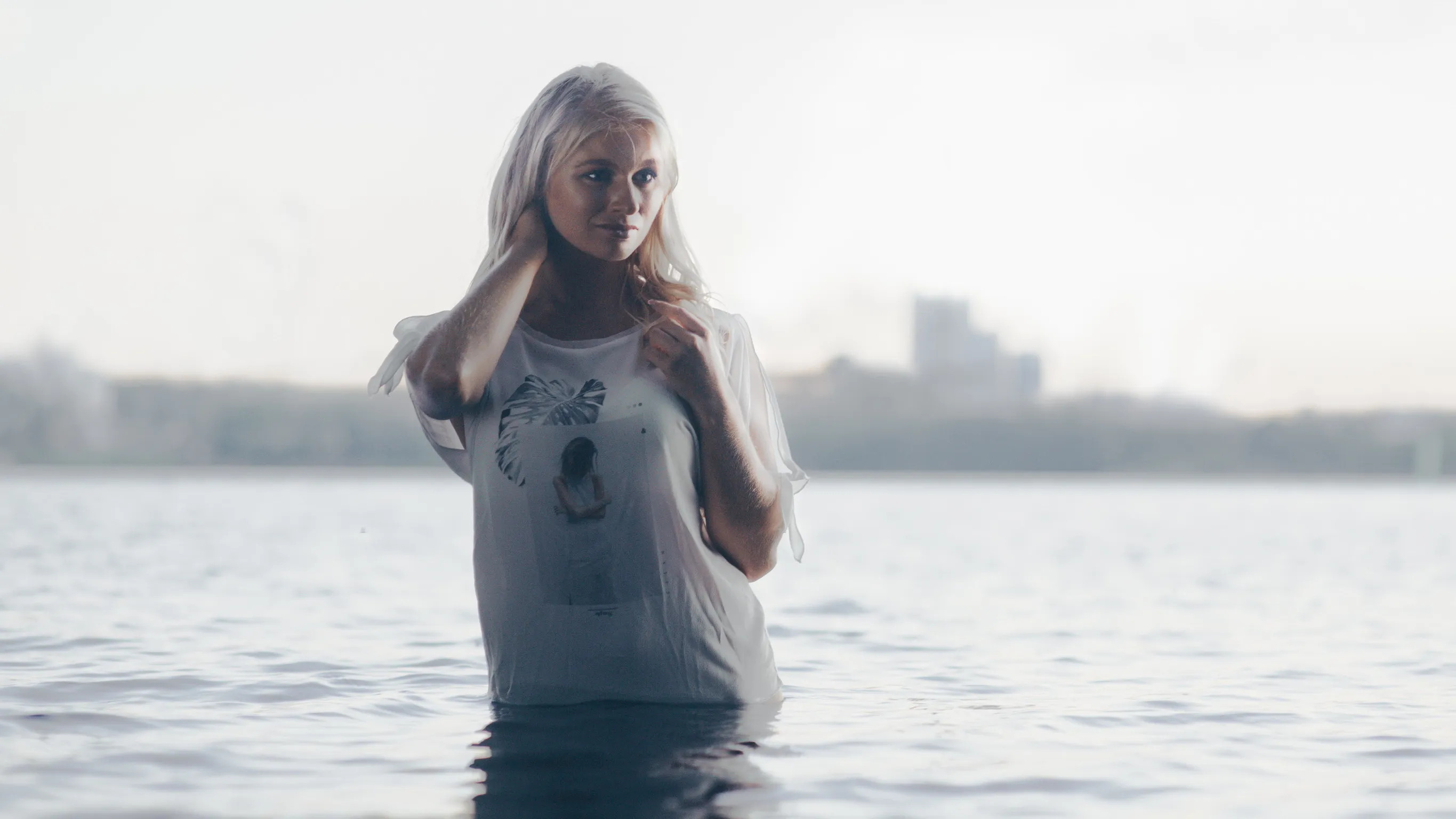 Emily standing in water wearing a white t-shirt with a graphic design.