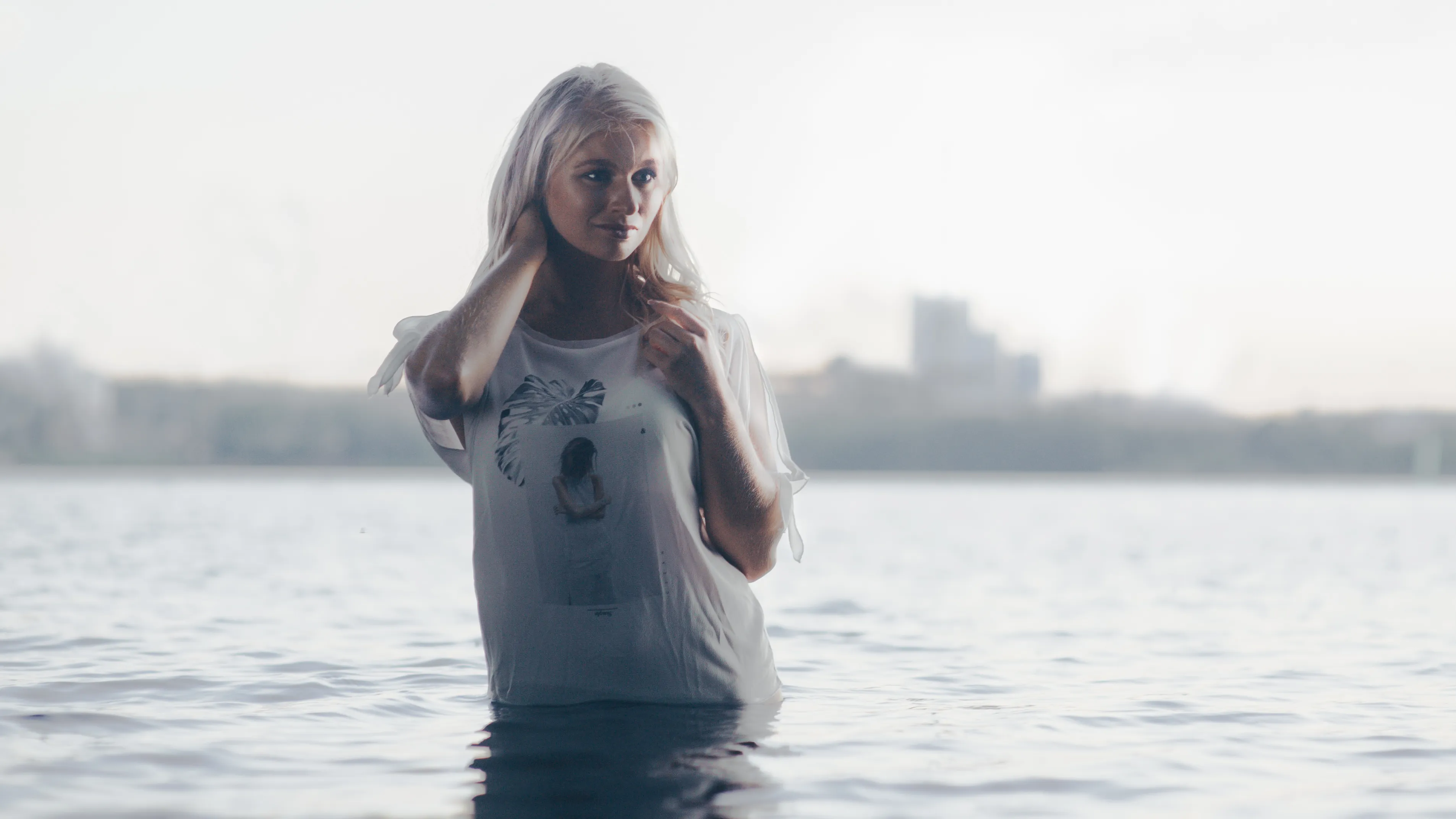 Emily standing in water wearing a white t-shirt with a graphic design.