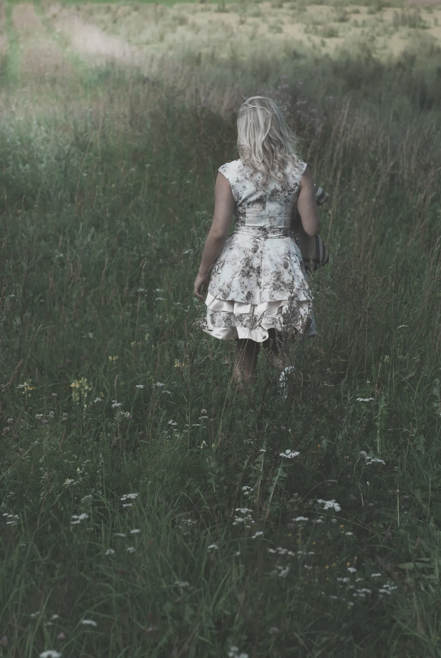 Emily walking through a grassy field in a floral dress.