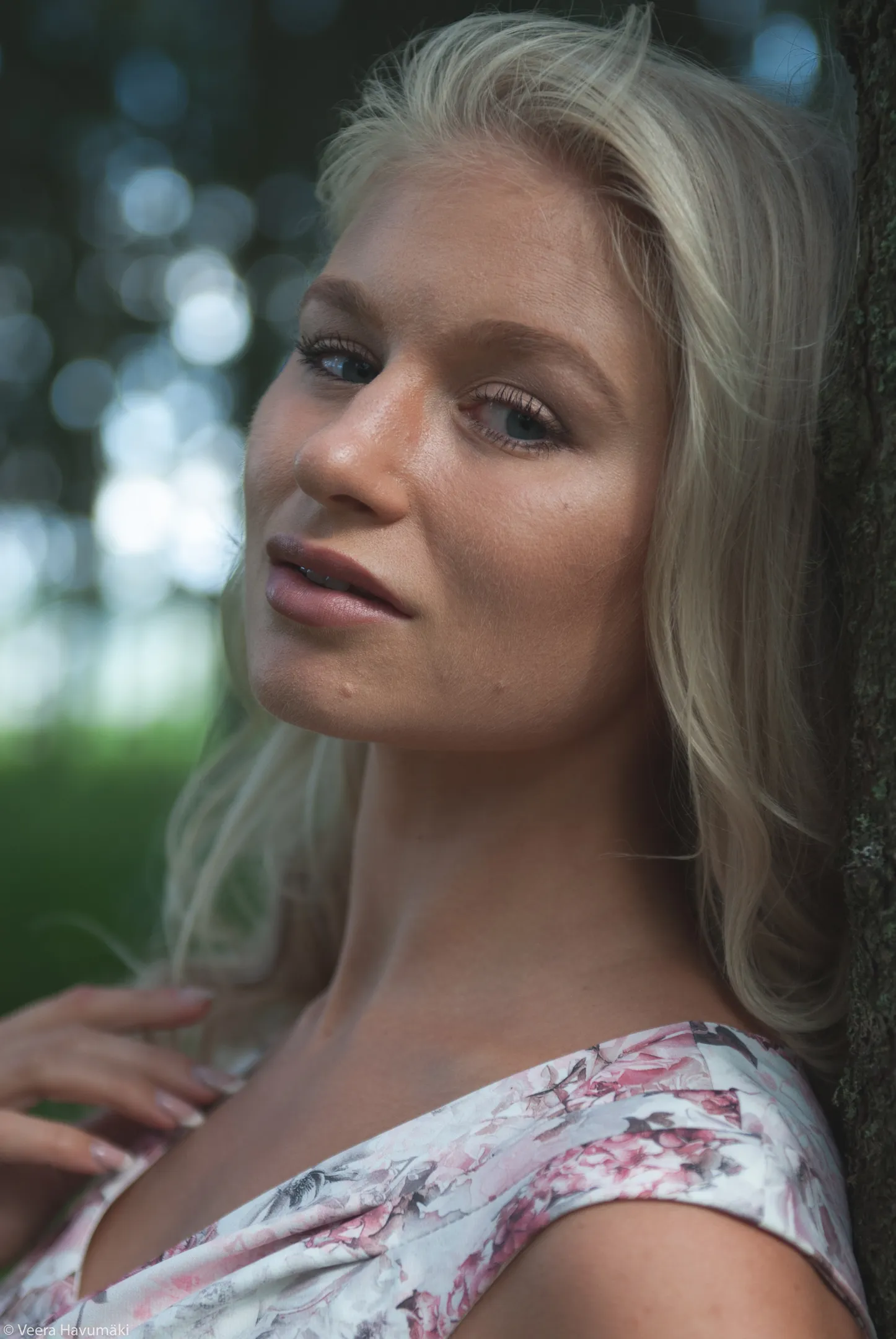 Emily posing outdoors with a serene expression, wearing a floral dress.