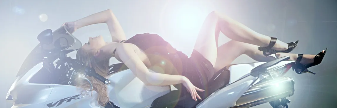 Emily posing on a motorcycle in a black dress and high heels.