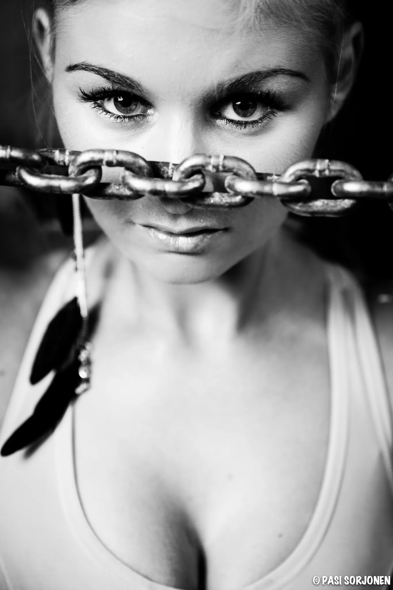 Emily posing with a chain in front of her face, wearing a tank top and earrings.