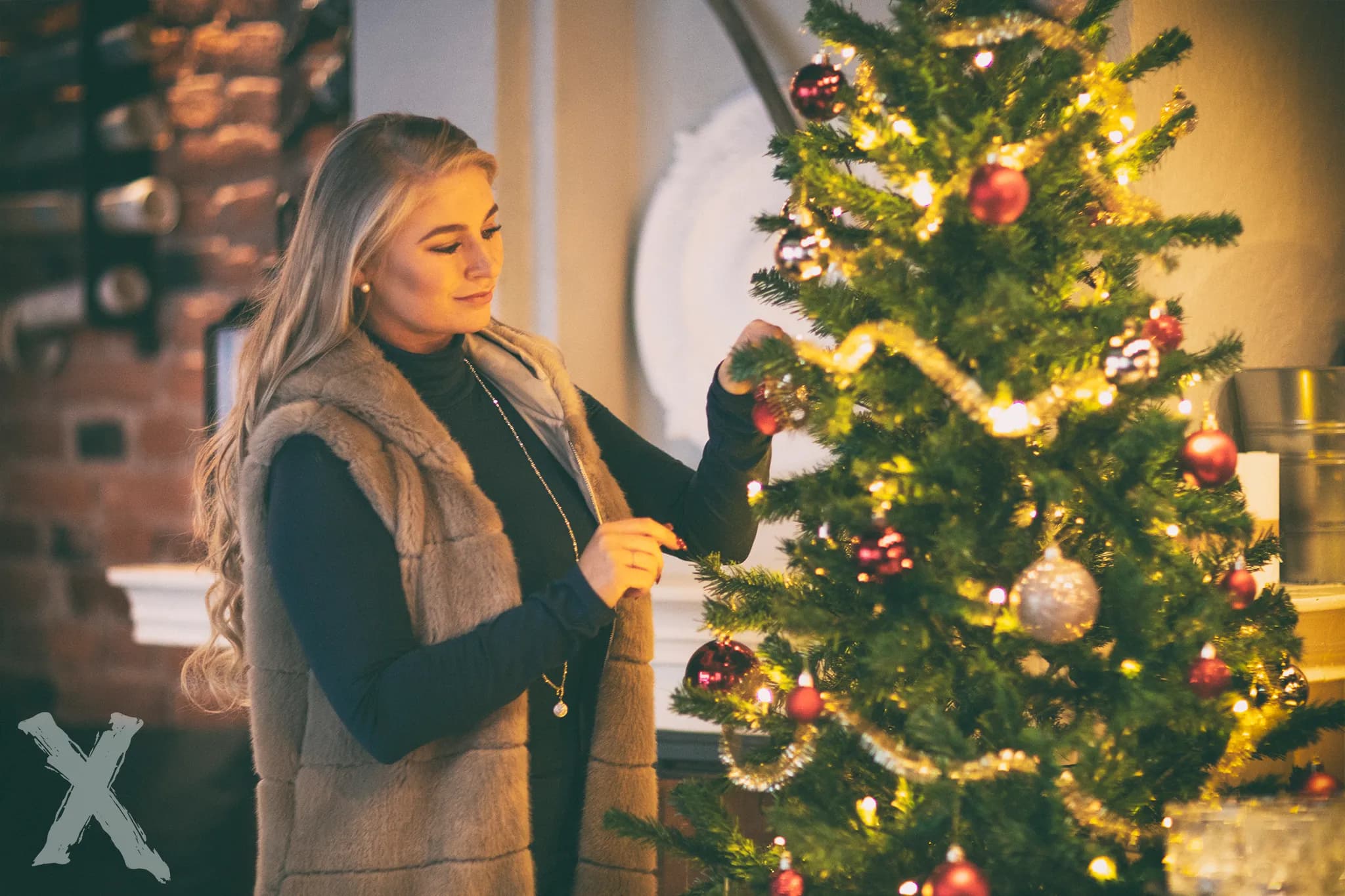 Emily decorating a Christmas tree with ornaments and lights.