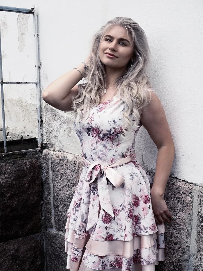 Emily posing against a wall in a floral dress.