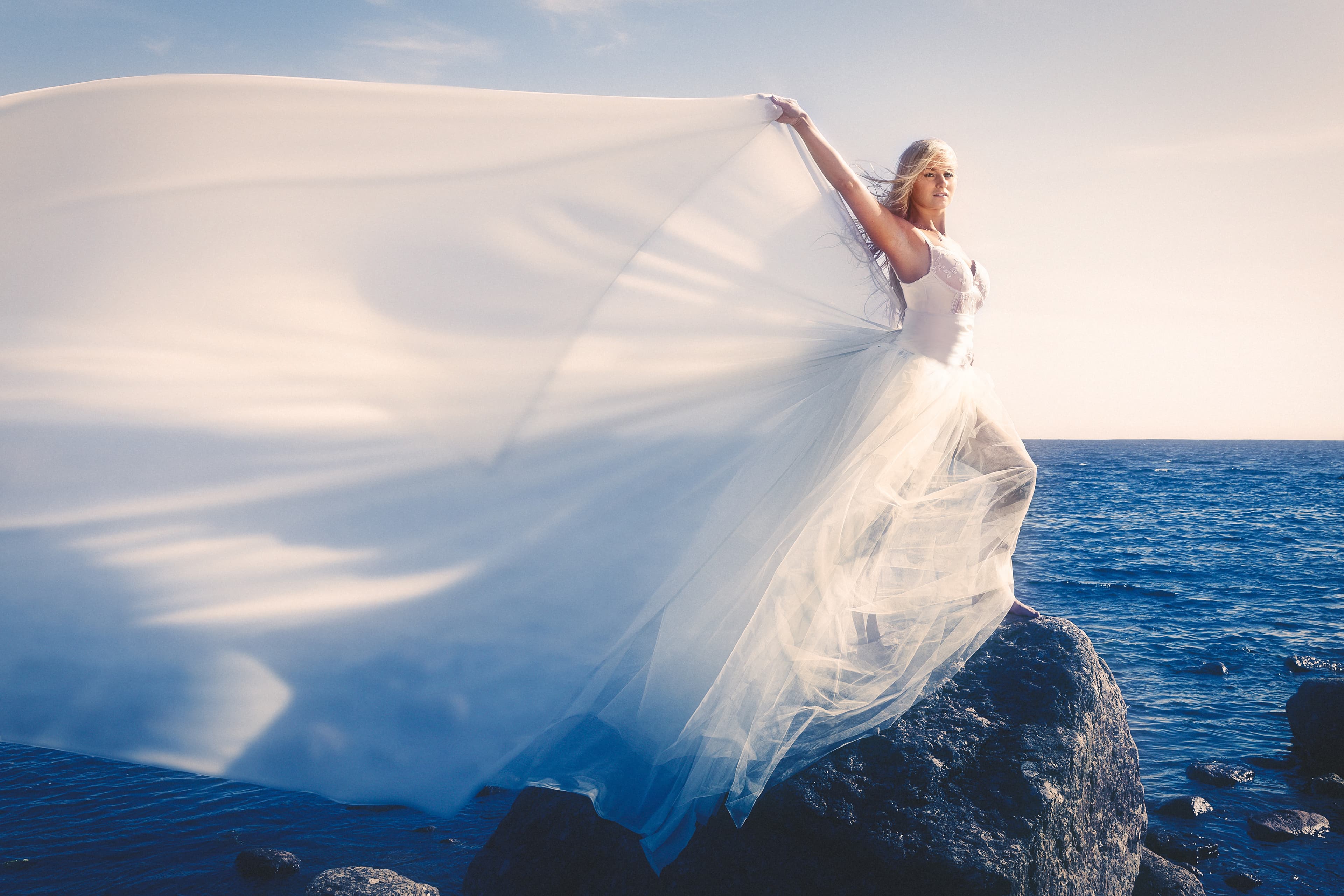 Emily in a flowing white dress by the ocean.